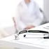 Stethoscope on desk with blurred doctor in background representing Medi-Cal Regulation Specialists coordinating care and medical services for clients