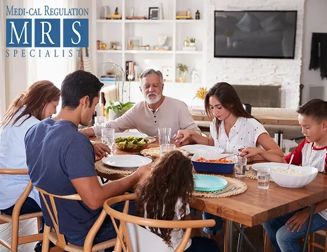  Multigenerational family praying at dinner table representing Medi-Cal Regulation Specialists supporting California families