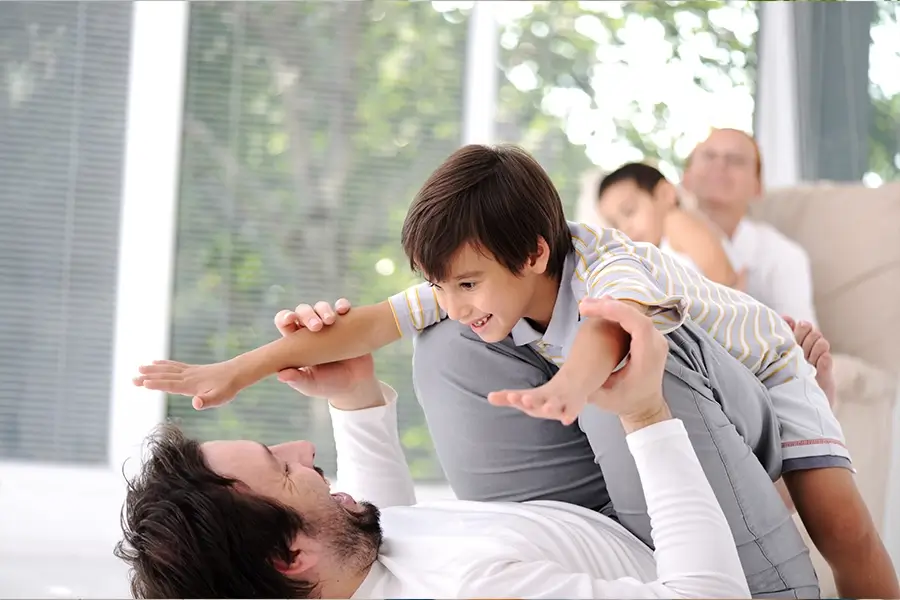 Father playing with his young son in a bright living room, symbolizing Medi-Cal services for non-seniors, including healthcare support for families, individuals, and children in need of medical assistance in California.