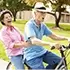 Joyful senior couple riding a bicycle together in the park representing Medi-Cal Regulation Specialists promoting active and healthy aging through long-term care planning
