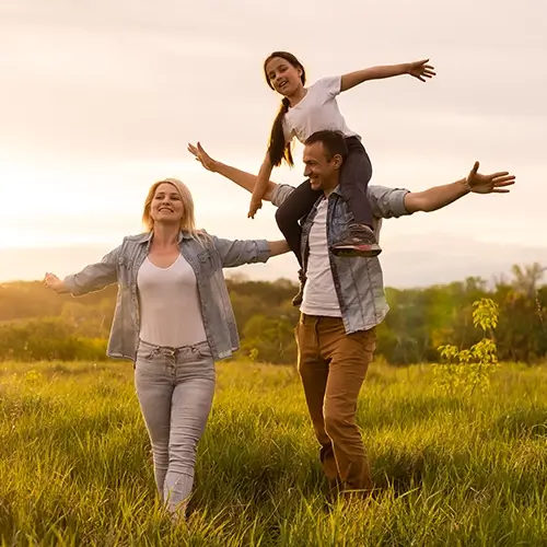 Happy family enjoying a walk in the field at sunset representing Medi-Cal Regulation Specialists assisting non-seniors with healthcare services and benefits